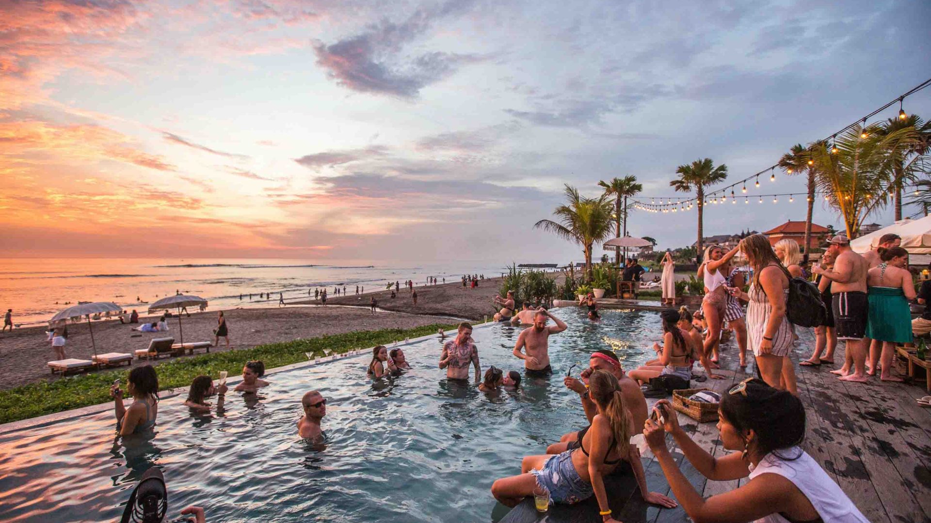 Tourists in a pool at sunset.