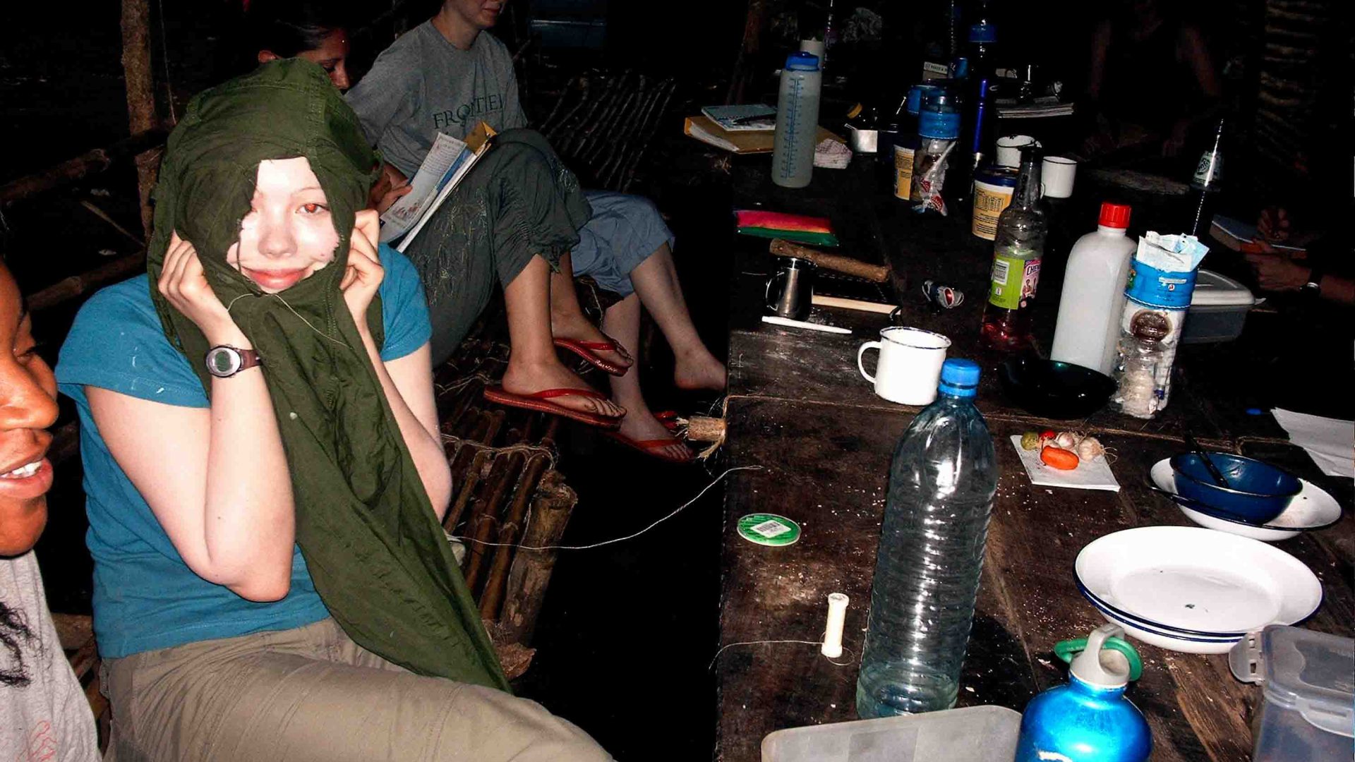 The writer Jennifer holds up a torn item she is repairing at a table.