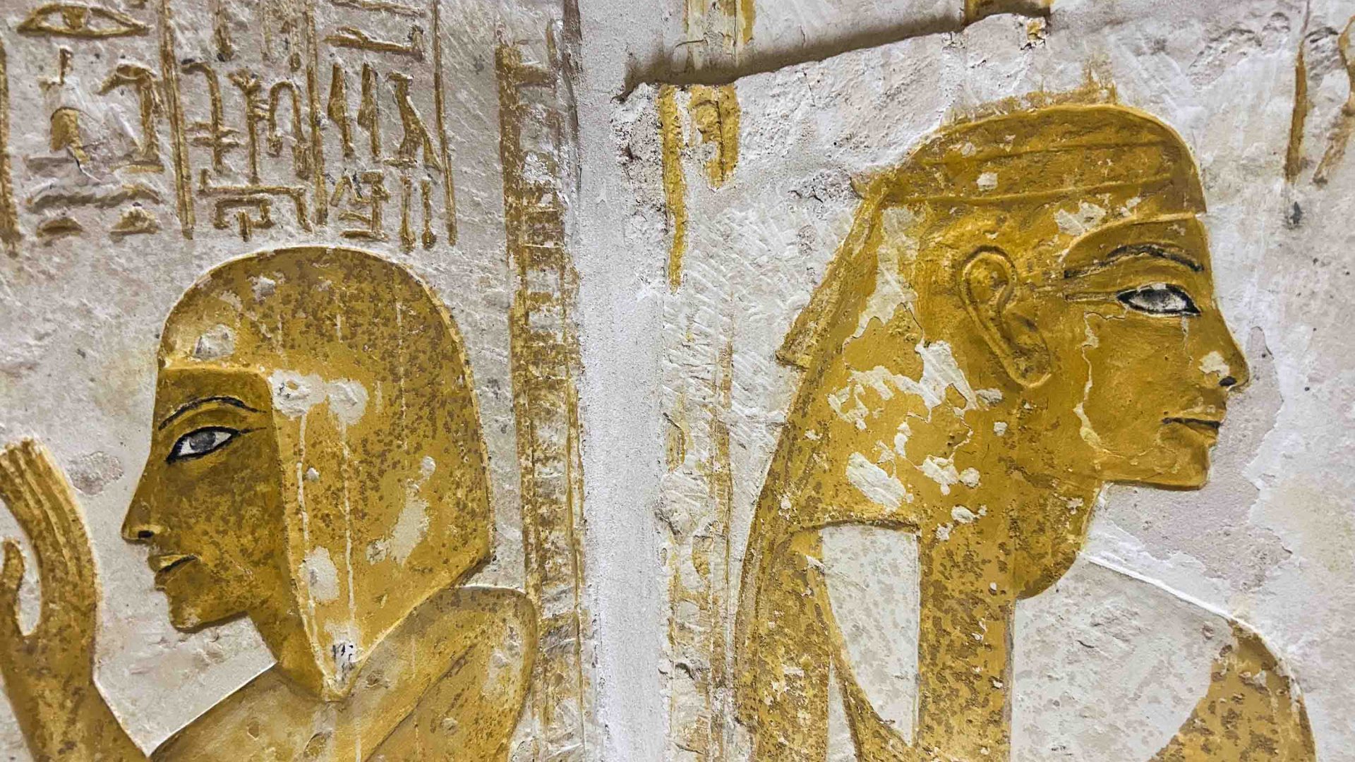 Golden hieroglyphics of people adorn a wall of the Maya tomb.