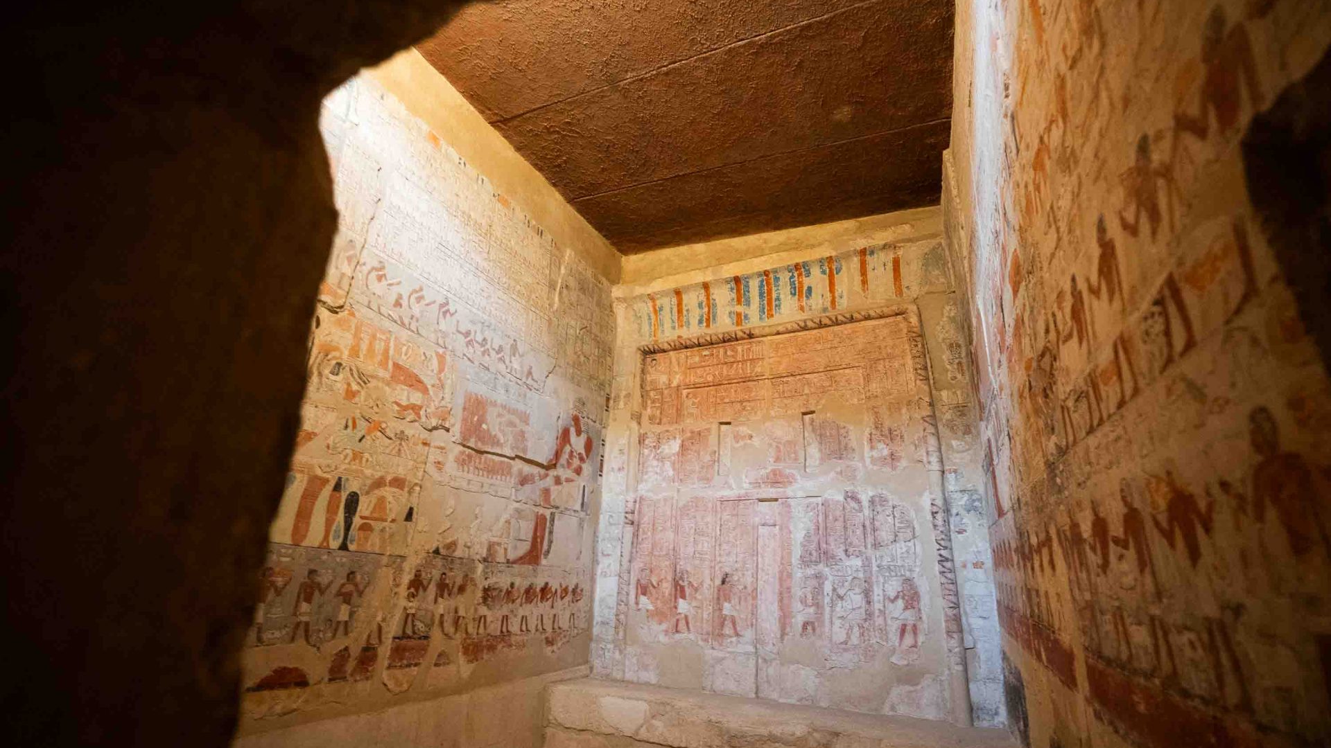 Interior of a room with painted walls depicting life in ancient Egypt.