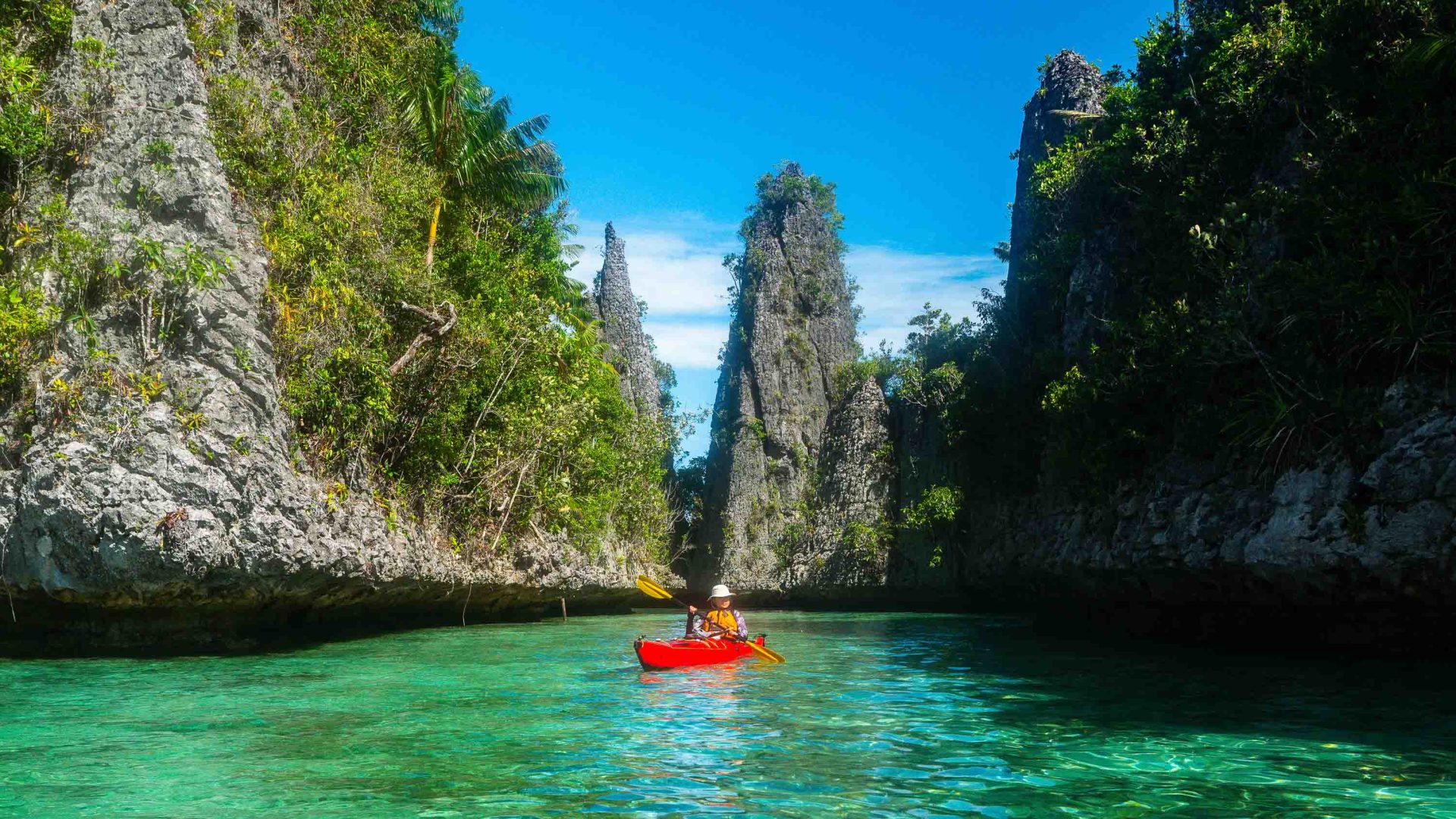 A woman paddles out of a narrow channel.