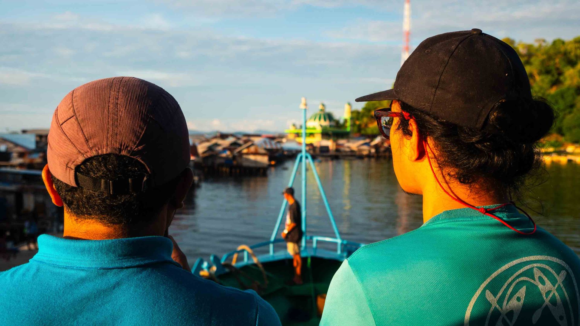 Two men stand at the front of a ferry and look at the area where they will pull in.