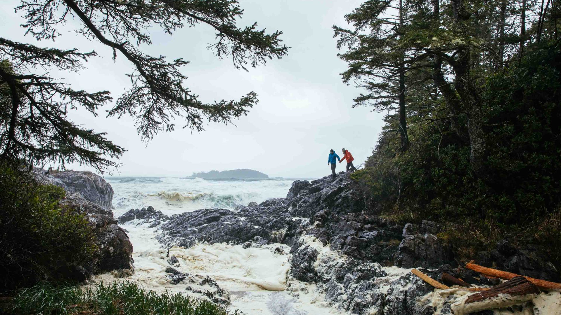 People clamber over rocks in rain jackets.