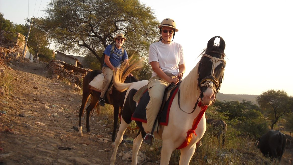 A father and daughter smile while horse-riding