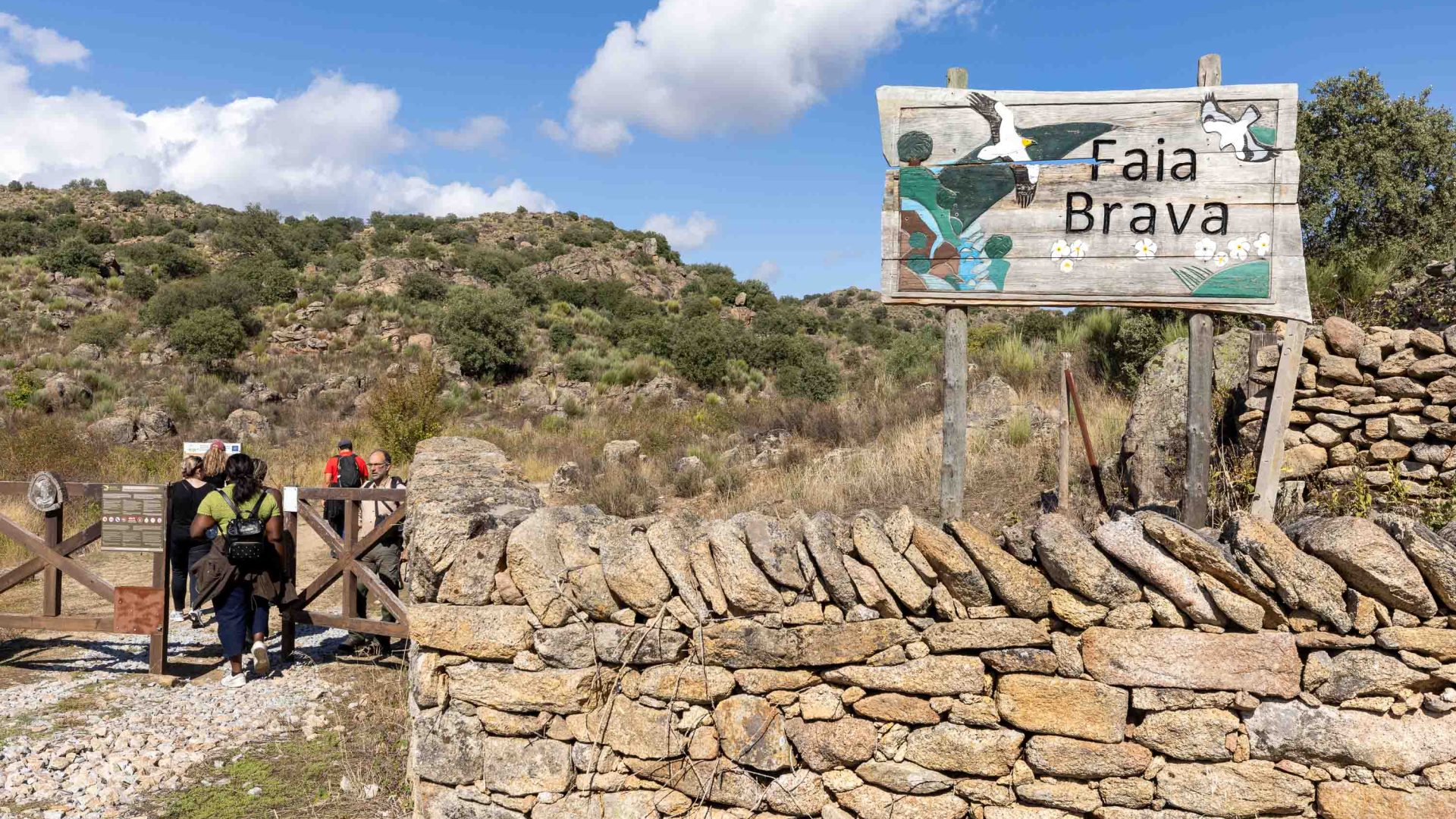 A group walks past a sign for the Reserve and a stone wall.