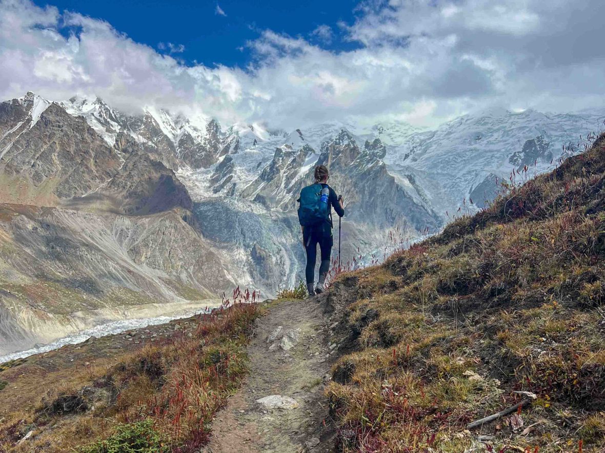 A woman walks solo toward a snowy mountain.