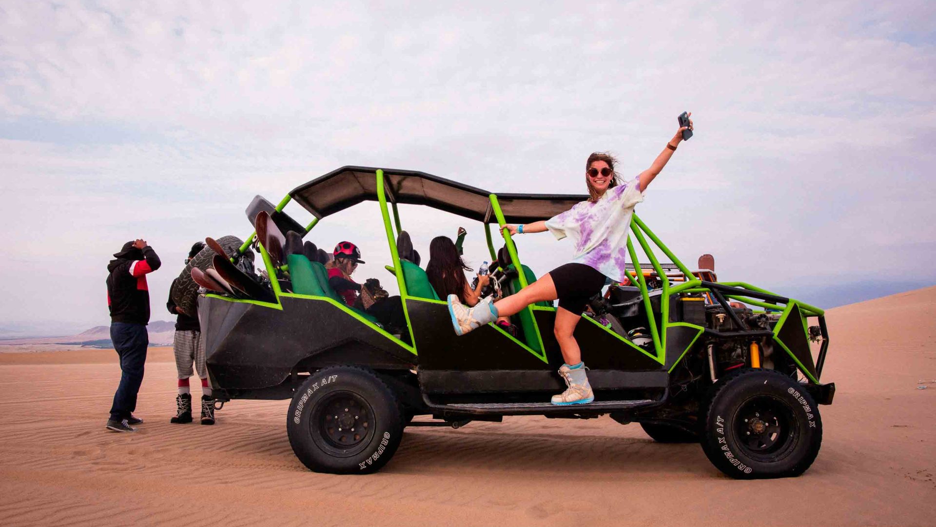 A group of women on a dune buggy. One waves her arm in the air.