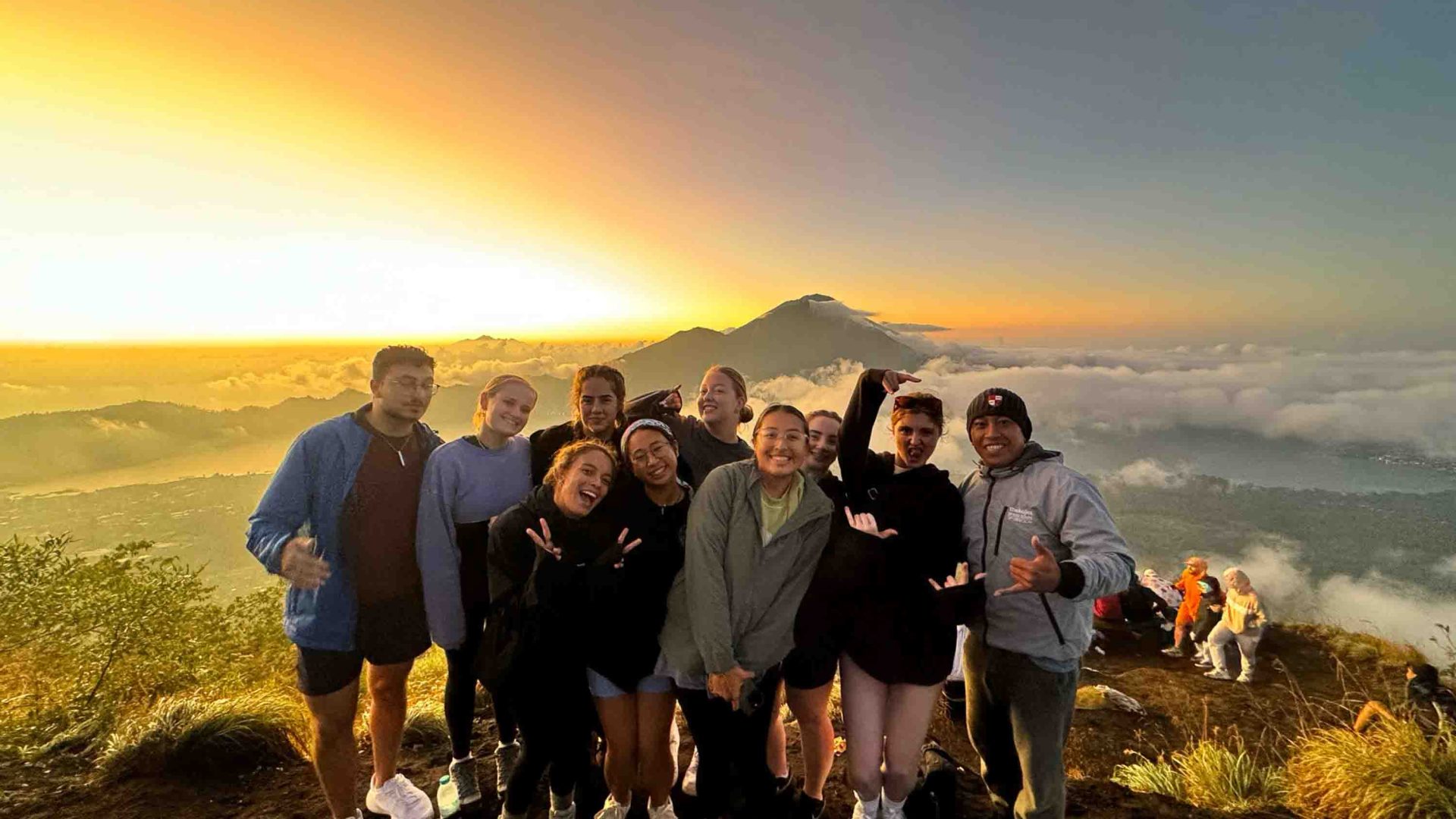 A group of women in a group portrait in front of as mountain at sunrise.