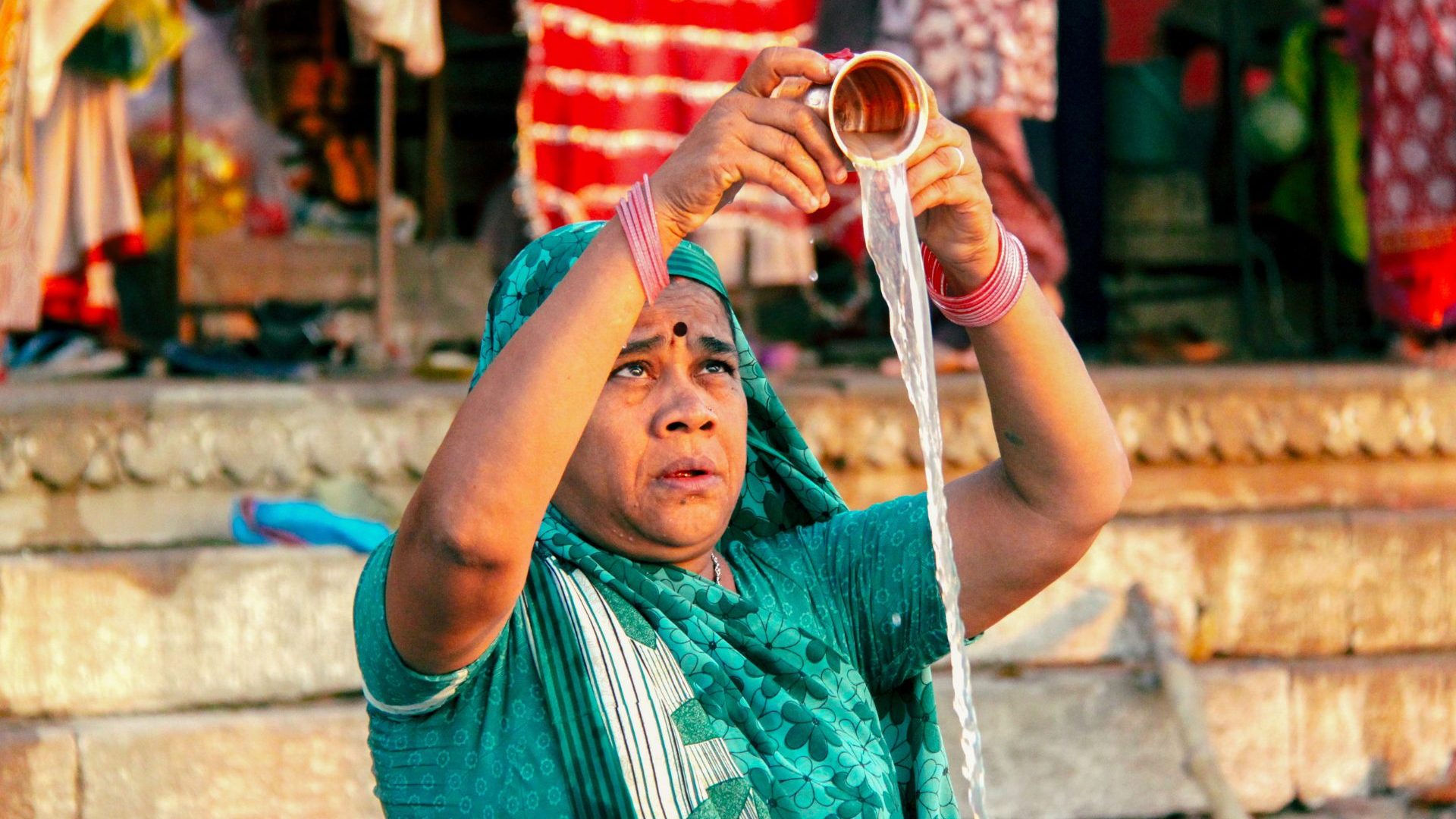 A woman pours holy water from a cup.