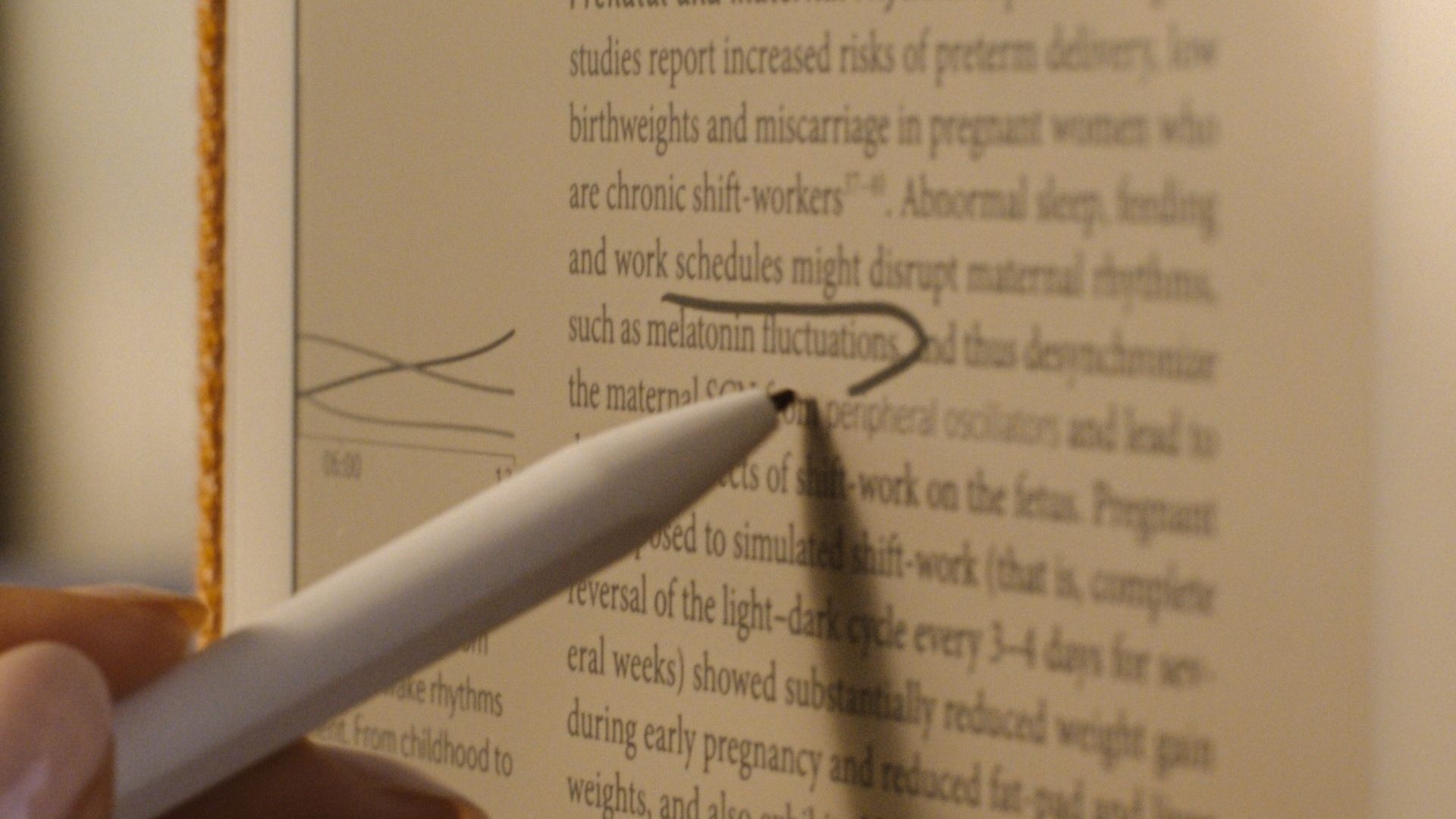 Close-up of a white stylus with black tip circling a word on the e-ink Daylight Computer tablet.