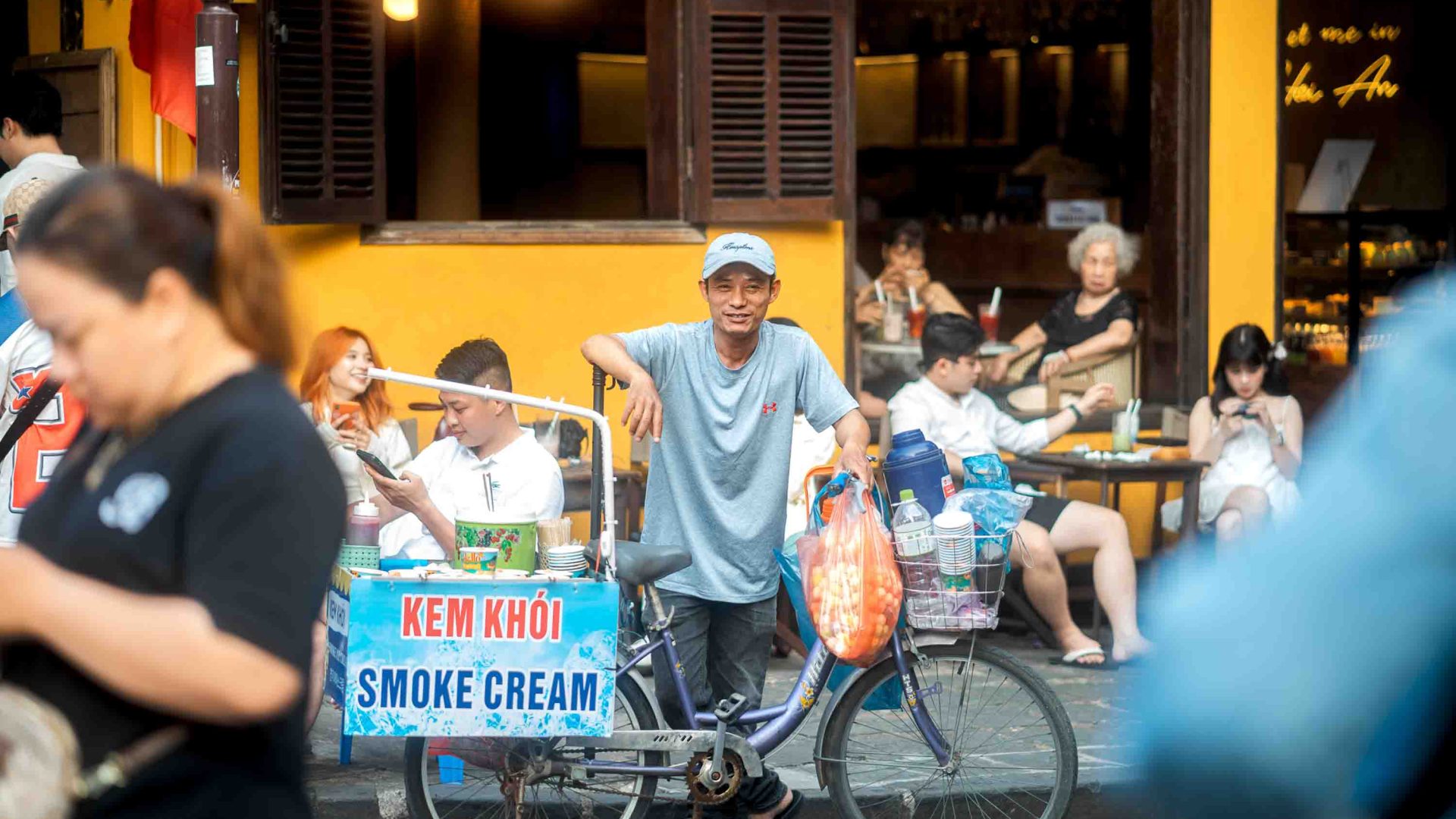 A street vendor selling 'smoke cream' from his bicycle is surrounded by people in the street.