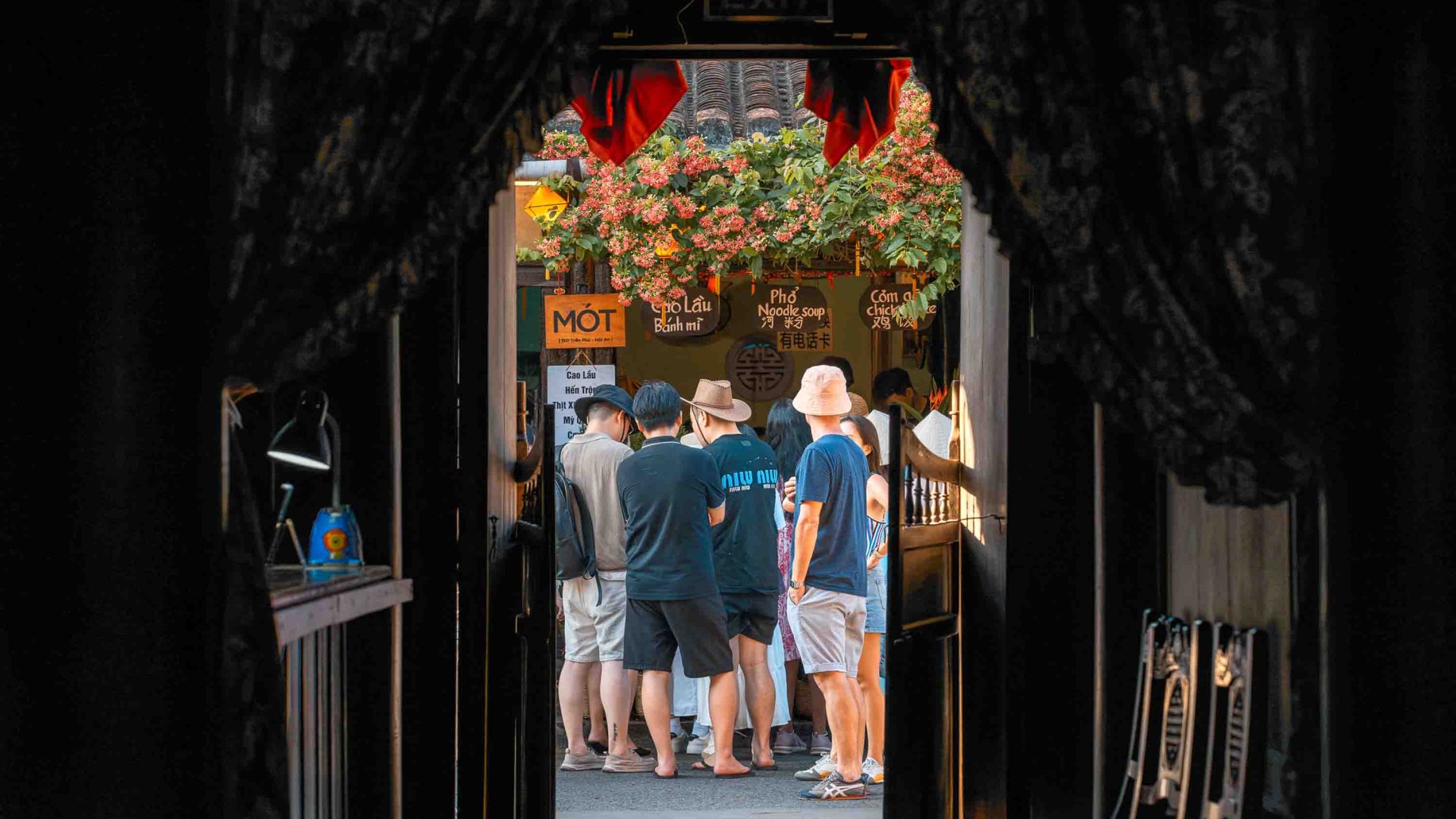 Looking through an arched doorway toward a group of people out the front of a tea shop.