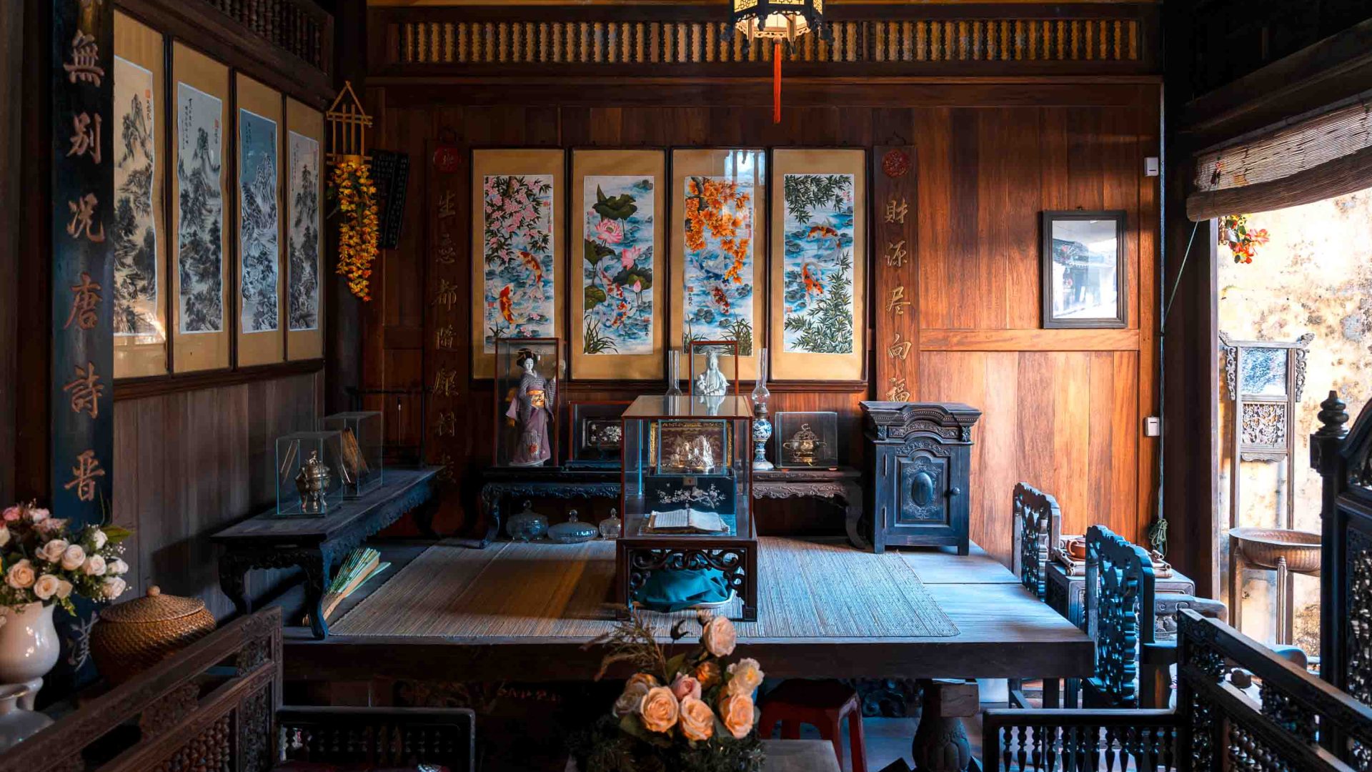 An interior with art on the walls, wooden panelling and a big table with chairs.