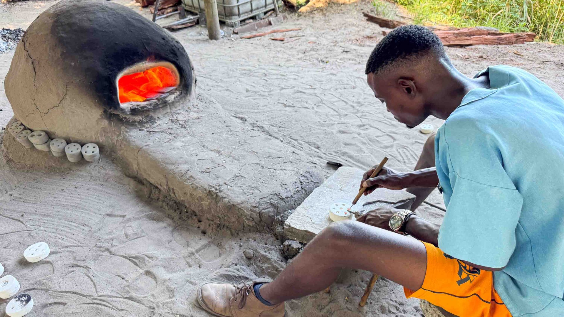 A man makes beads next to a kiln.