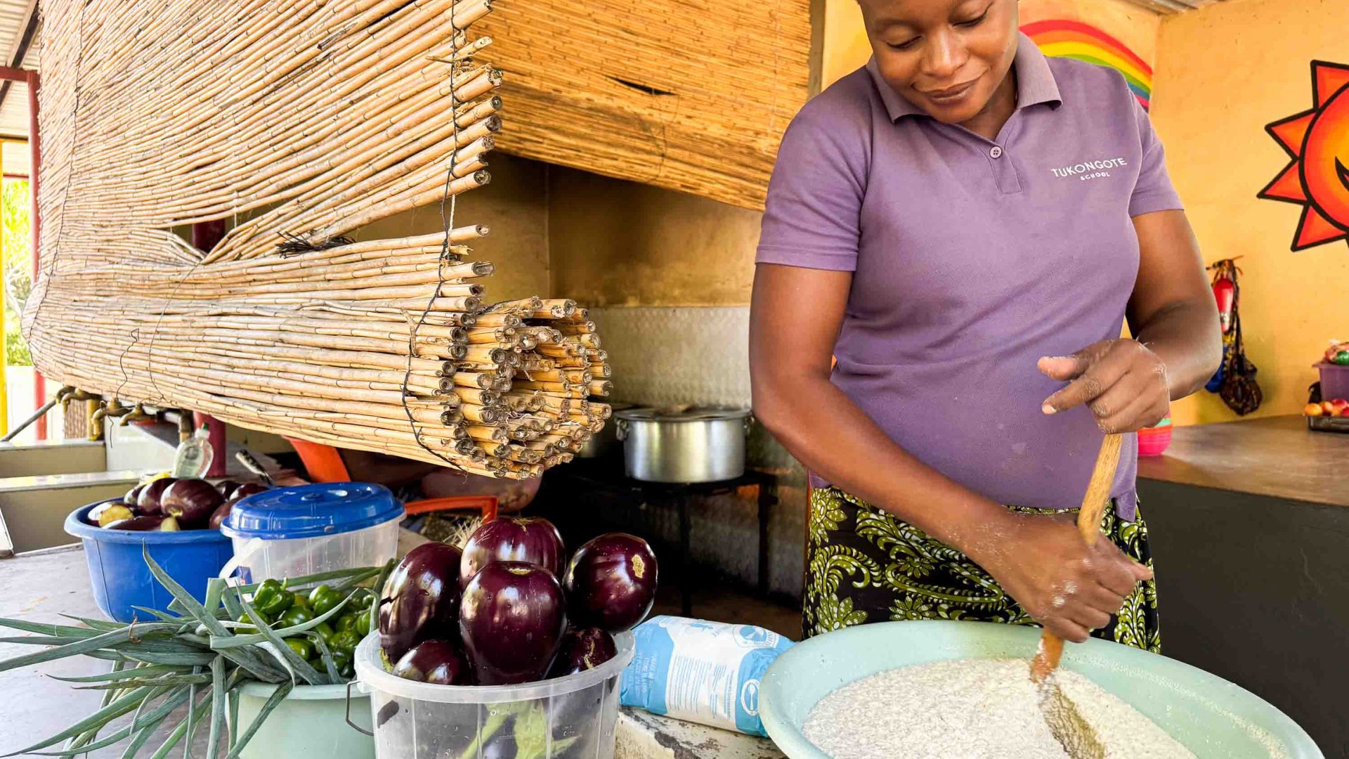A woman prepares food by mixing a bowl. She has vegetables next to her.