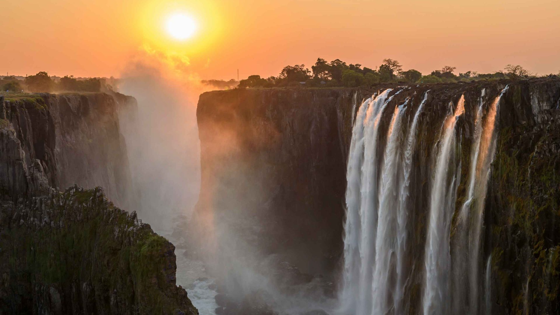 Water thunders down a waterfall at sunset.