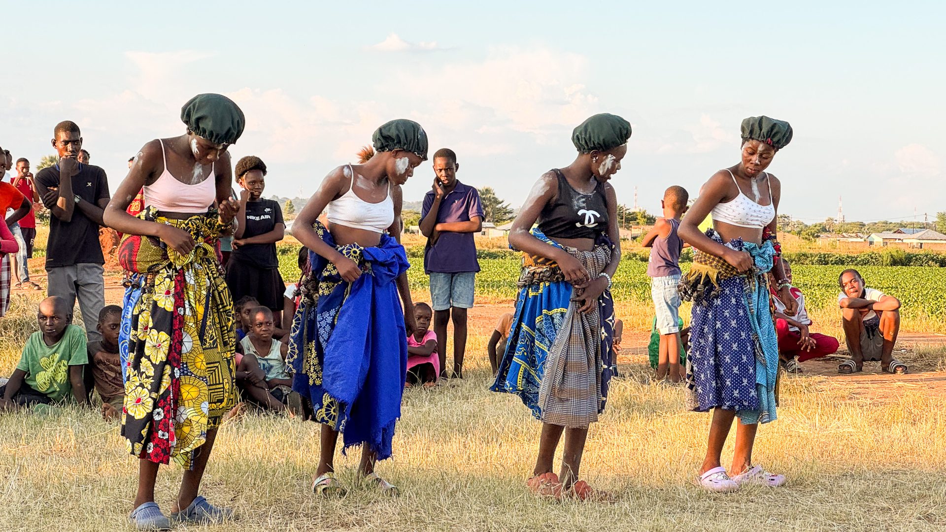 Women dance in a row wearing colourful clothing.