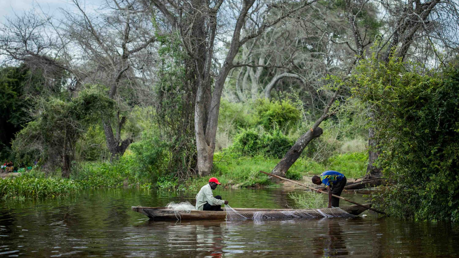 Fisherman nets are inspected on a small boat in a river.