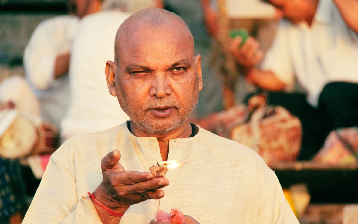A portrait of a man by the river, holding a candle as an offering