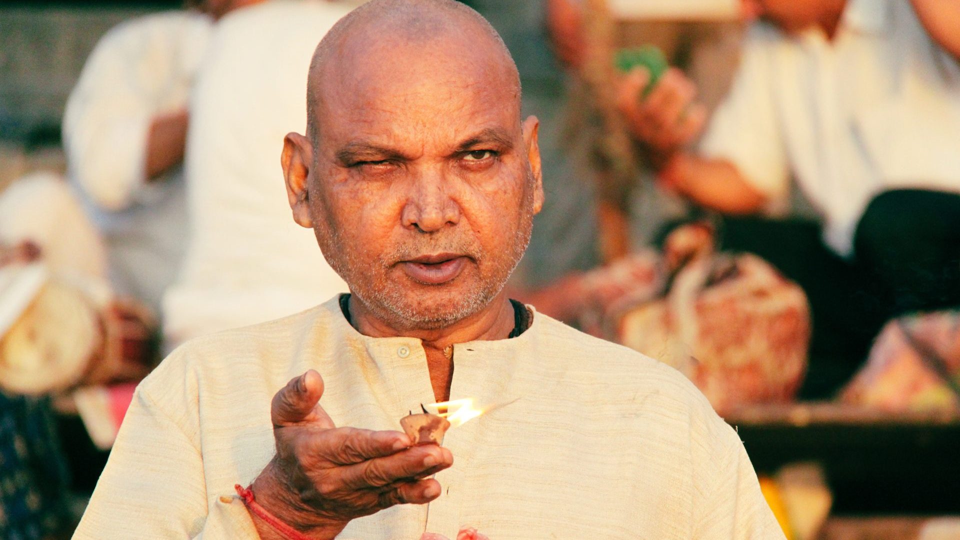 A portrait of a man by the river, holding a candle as an offering