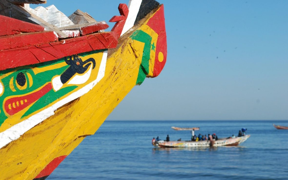A colorful boat in Senegalese flag colours at sea.