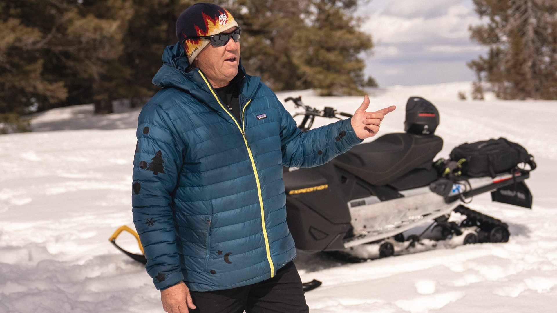 Man wearing blue ski jacket stands in snow