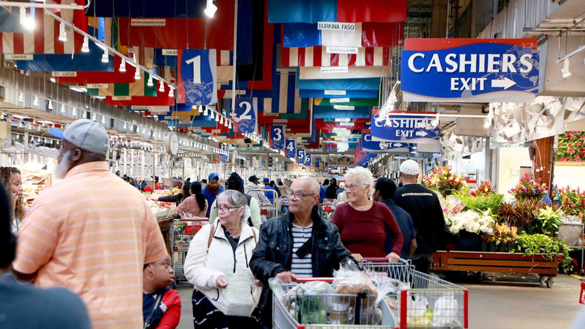 People push shopping carts through a grocery store.