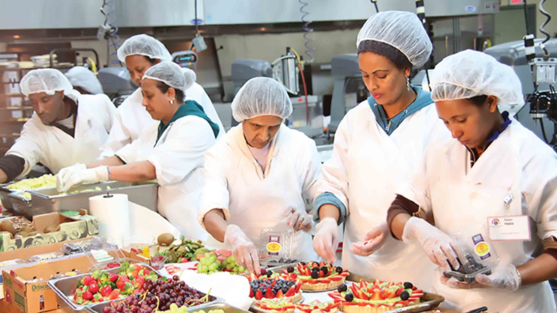 Employees add fruit to cakes.