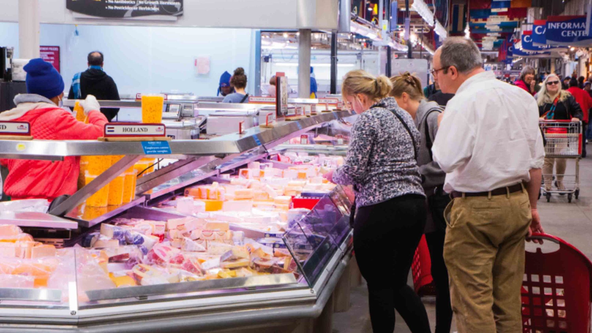 People peruse the meat and fish in a grocery store.