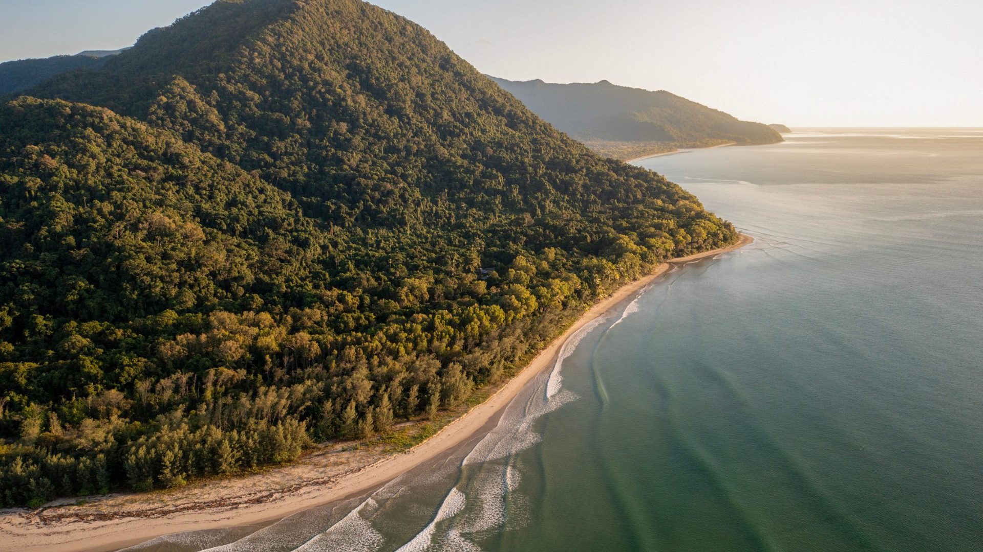 Aerial photo of rainforest, beach and ocean at sunset