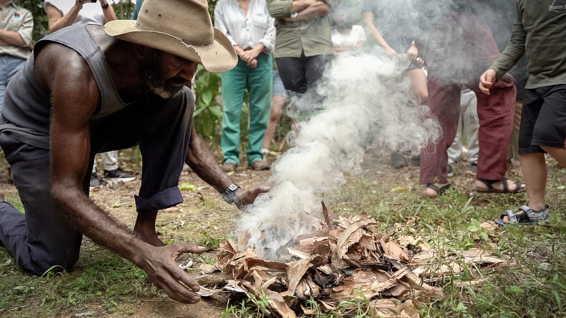 First Nations man kneels are fire during traditional ceremony