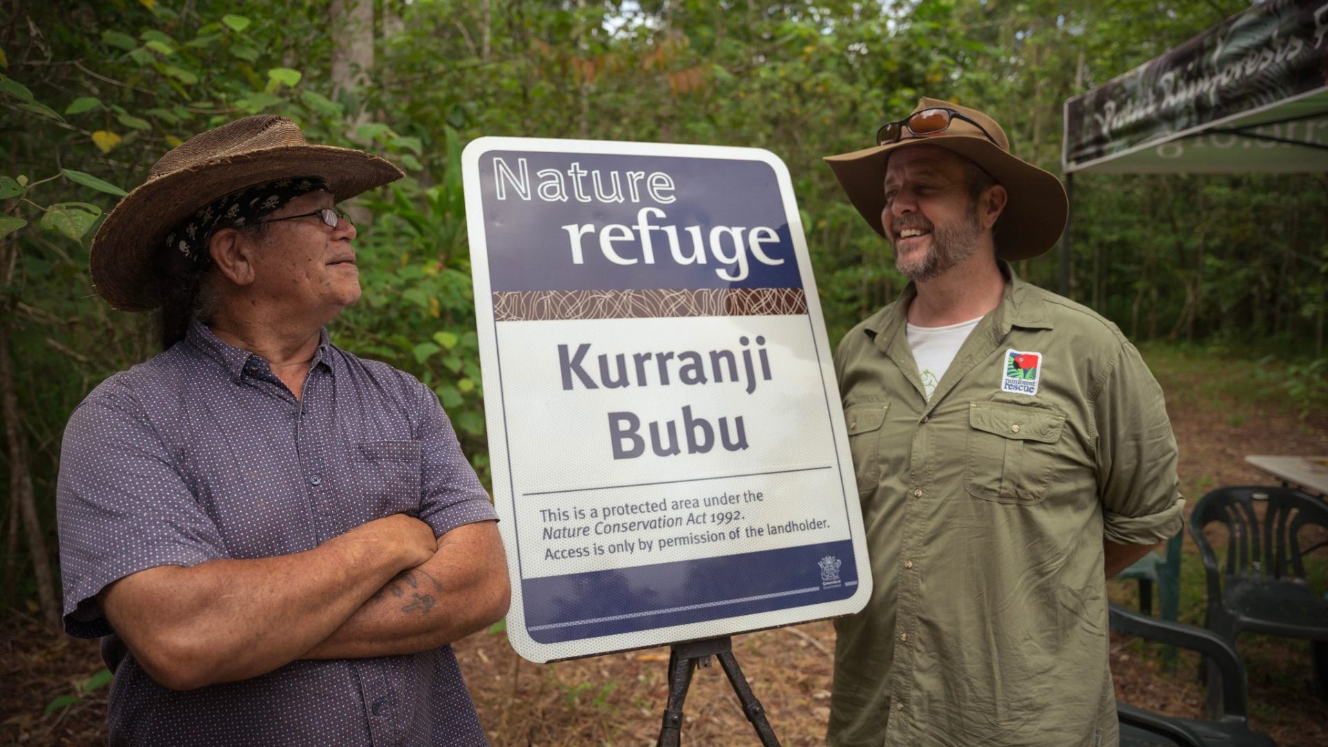 Two men stand in front of a sign saying 'Nature Refuge Kurranji Bubu'