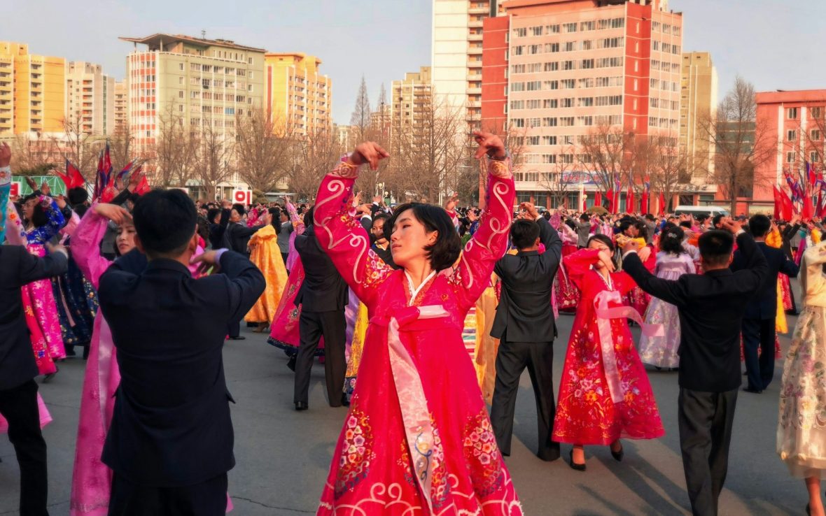 A woman wearing red traditional dress dances in a square