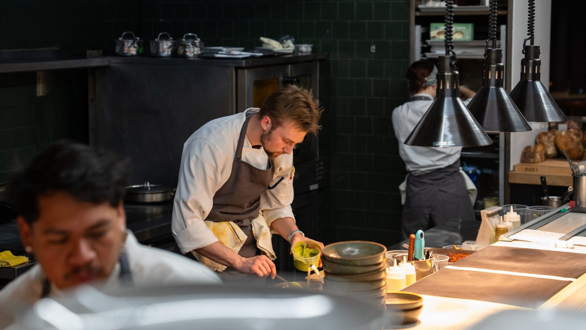 Three chefs work in a dark kitchen.