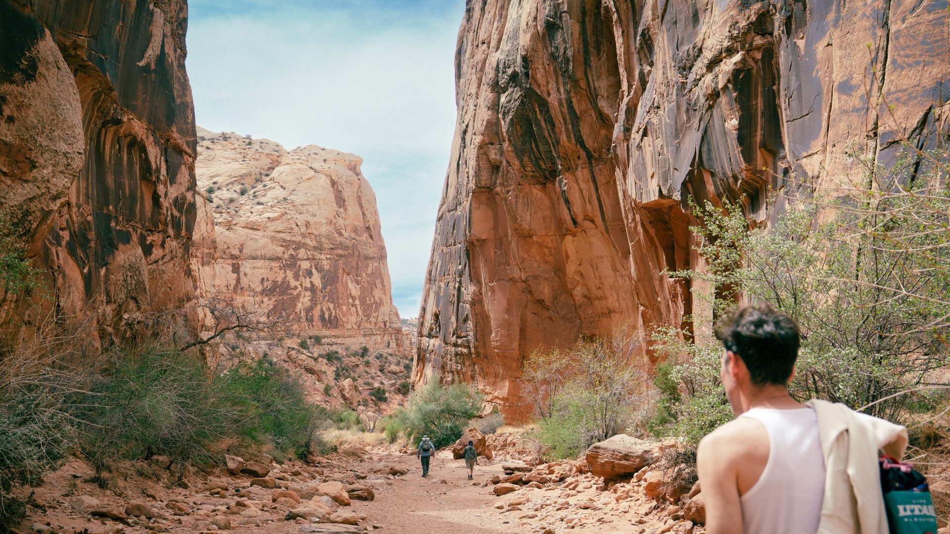 Man in white single walks in a red sandstone canyon