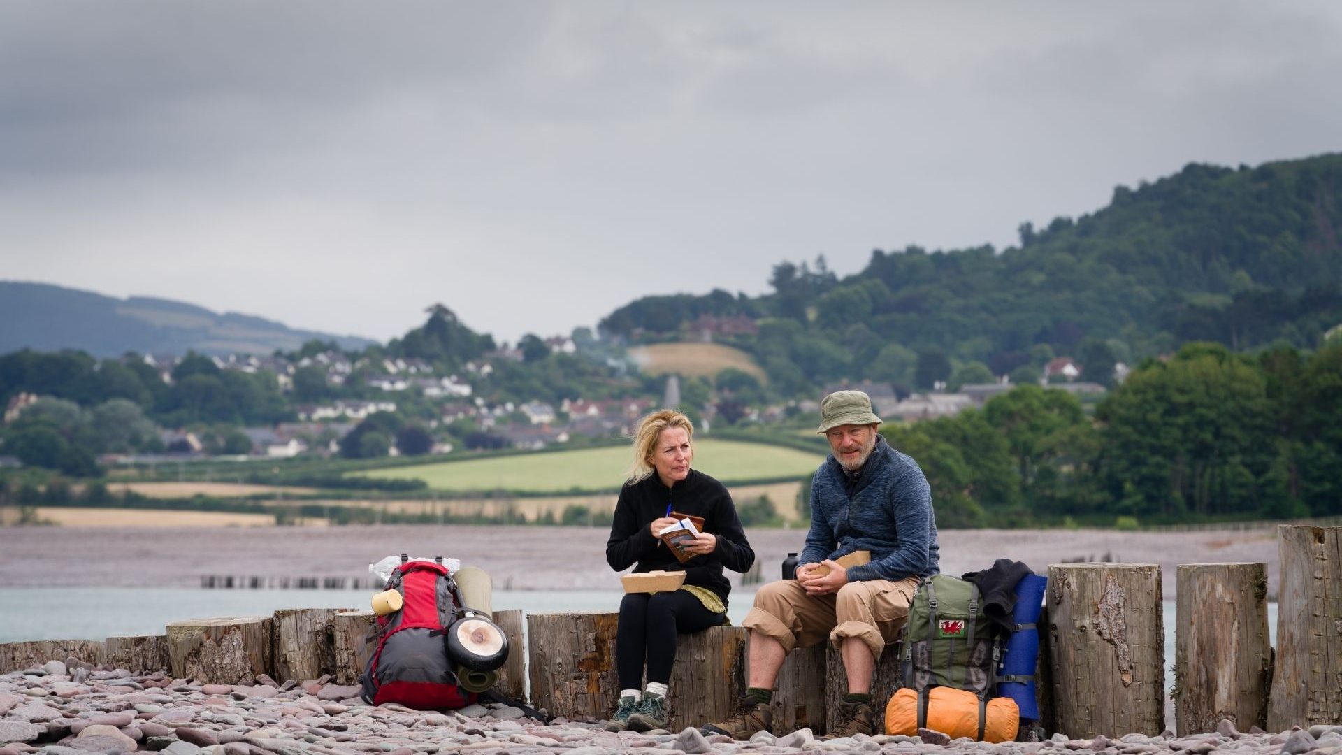 A man and woman on a hike take a break for lunch.