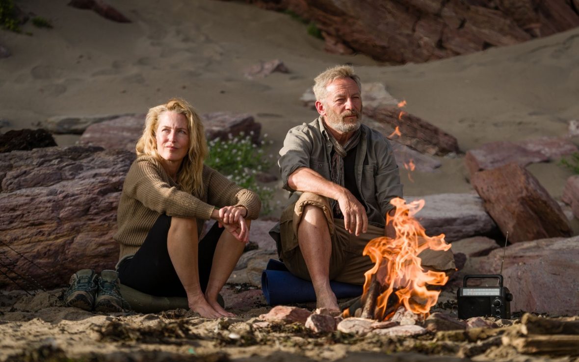 A man and woman on a hike sat by a campfire.