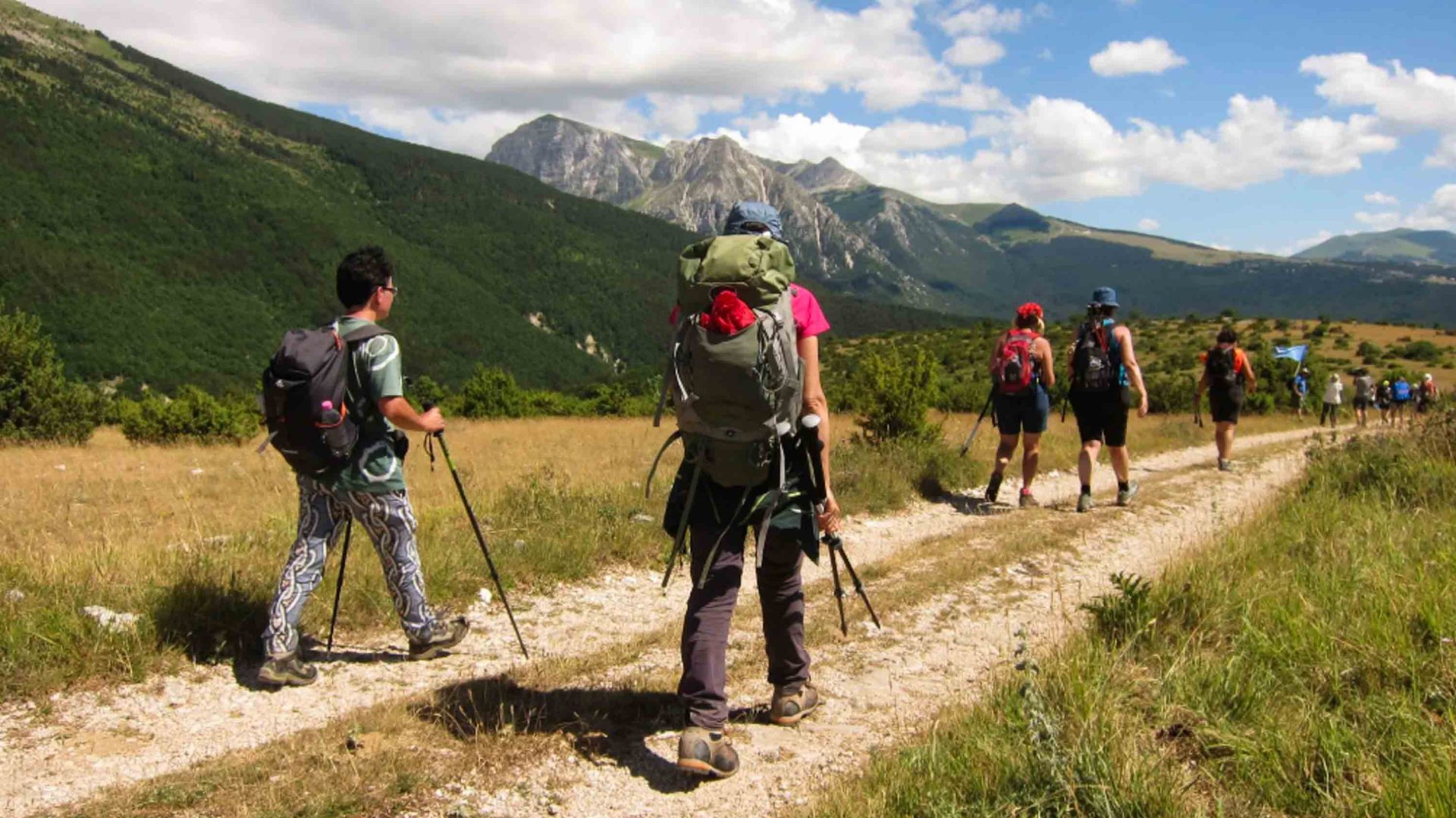 People walk along a trail in the mountains.