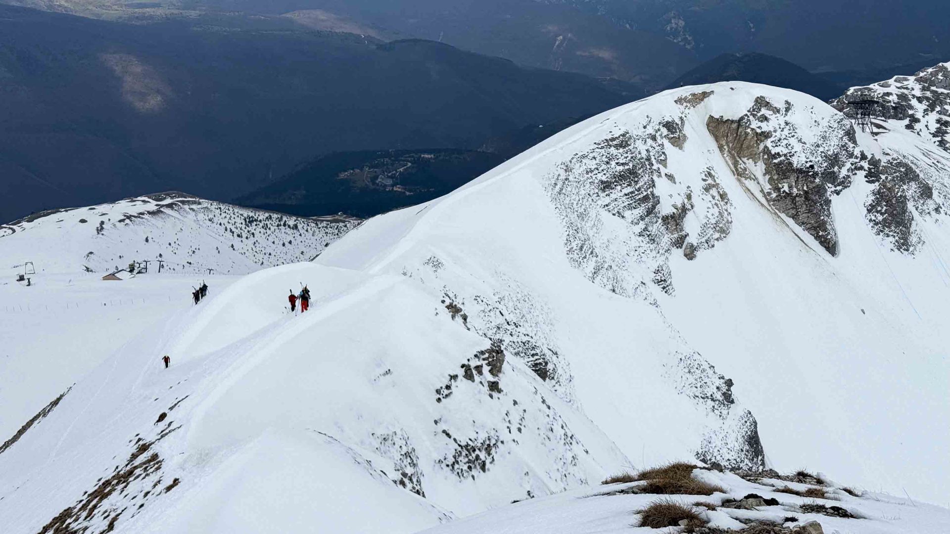 Two people walk across a snowy mountain.