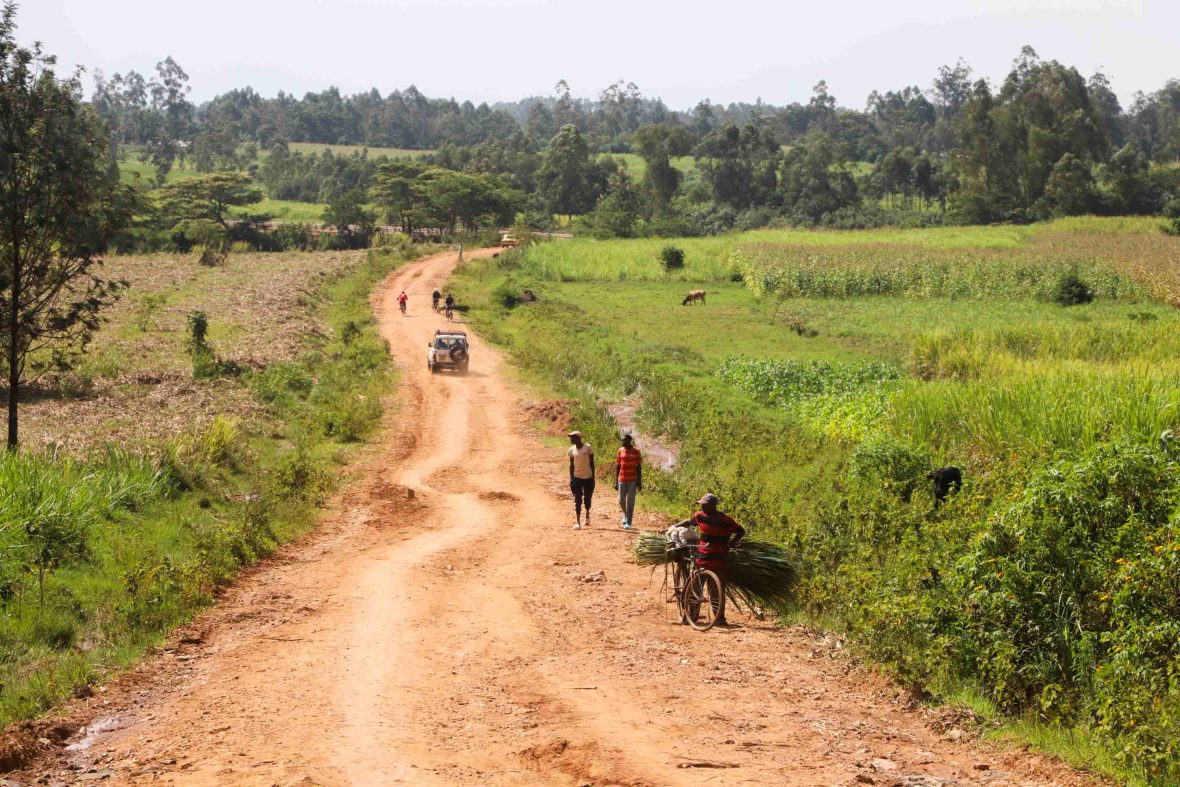 A man pushes his laden bike up a dusty road
