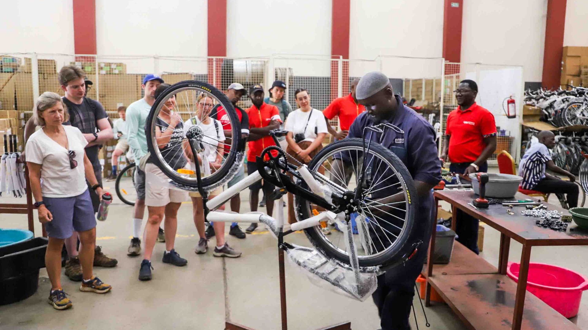 A bike mechanic looks at a bike while others watch on.