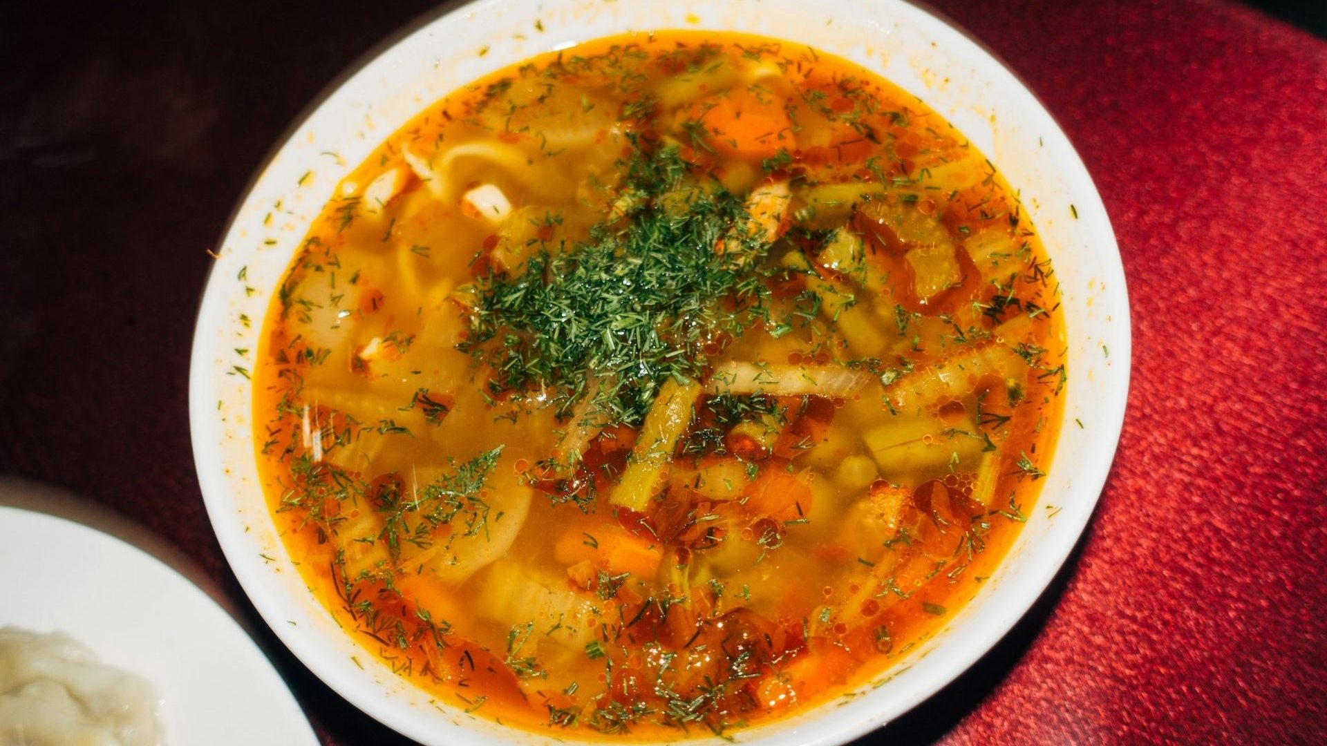 A bowl of soup packed with vegetables and herbs