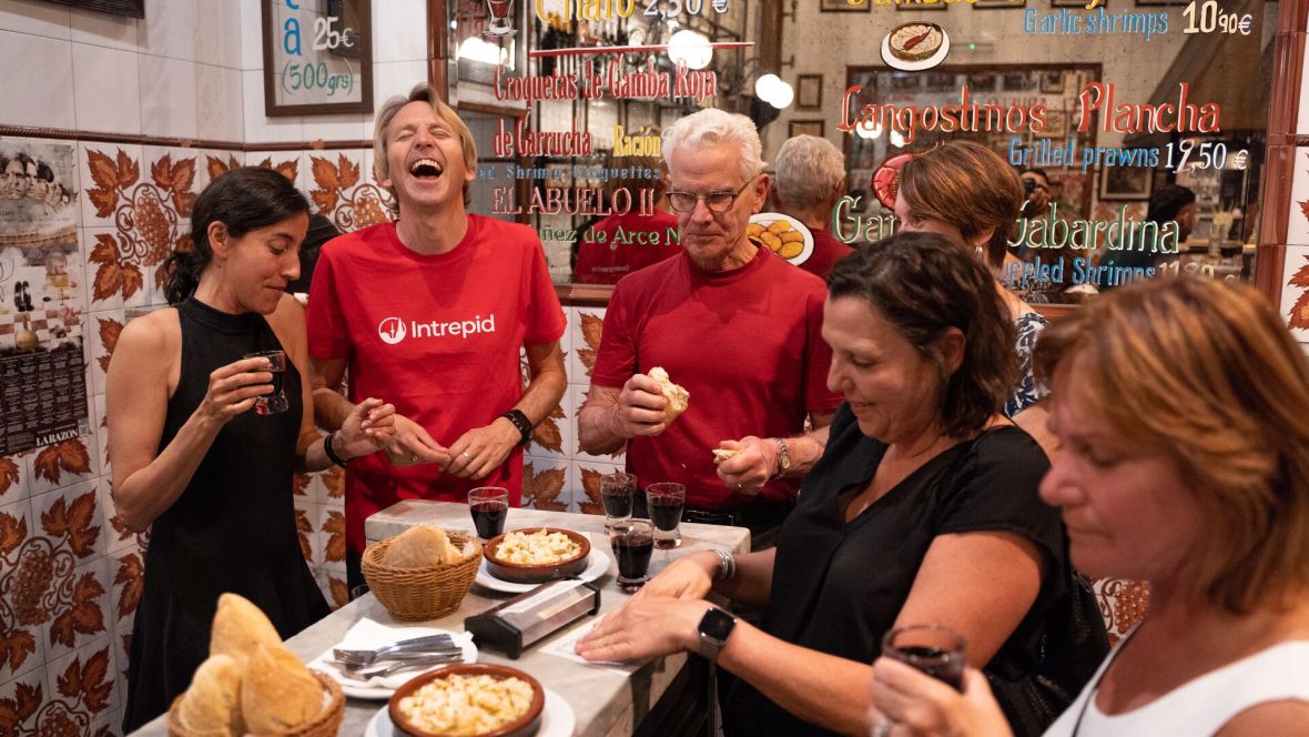 A group of travelers and an Intrepid guide enjoy a tapas meal in Madrid.