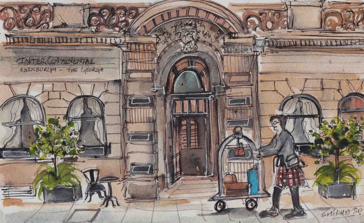 A bellboy pushes a cart past the doorway of a stone hotel.