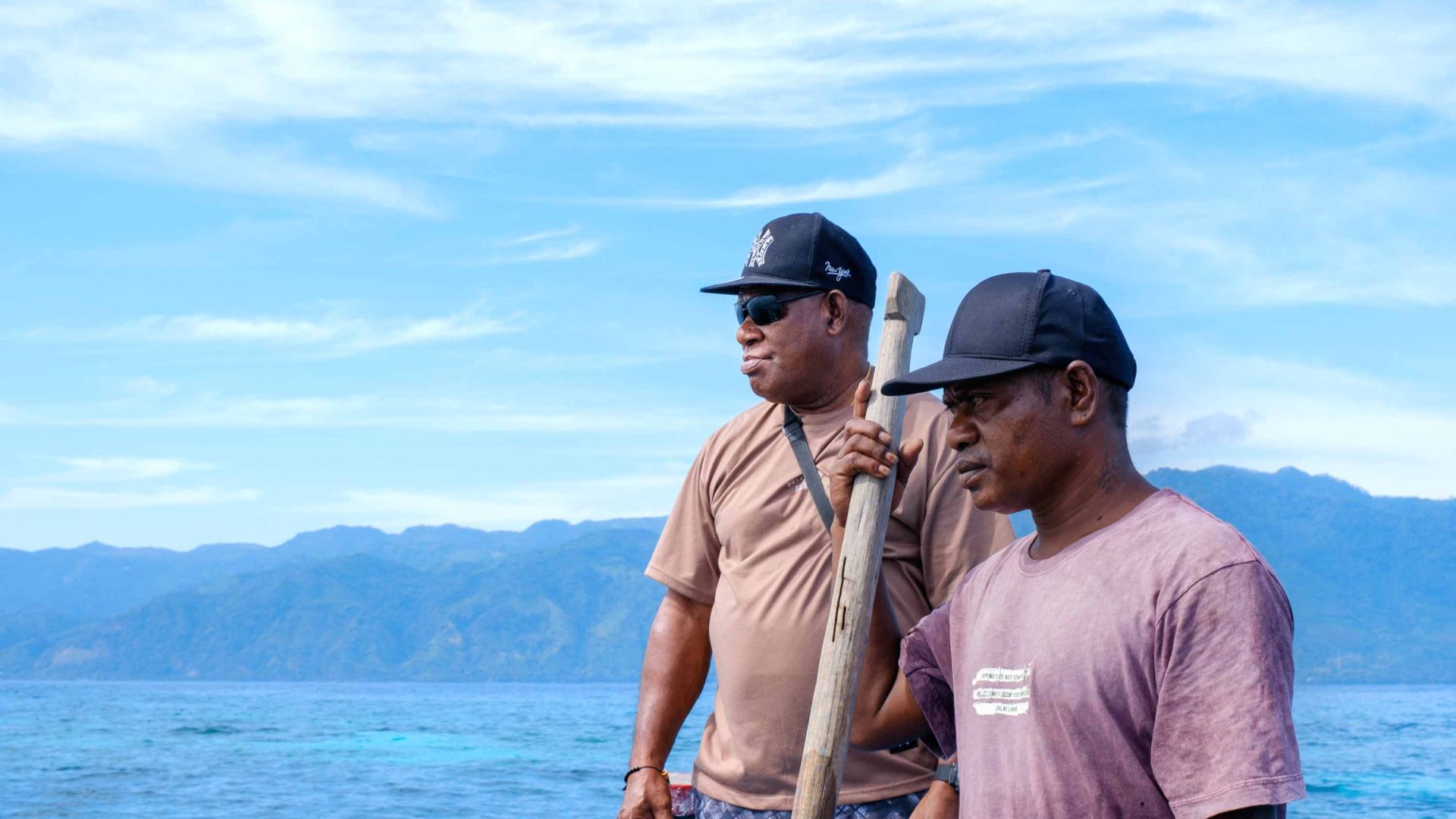Two men look out to sea from a boat.