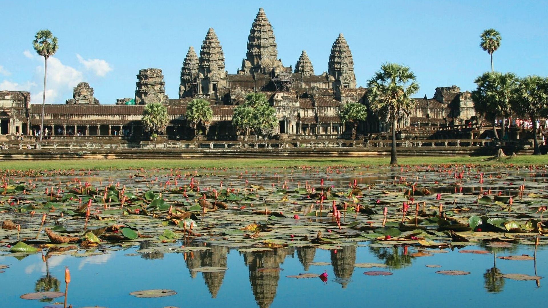 The Hindu-Buddhist temple complex of Angkor Wat and its five towers reflected in the water.