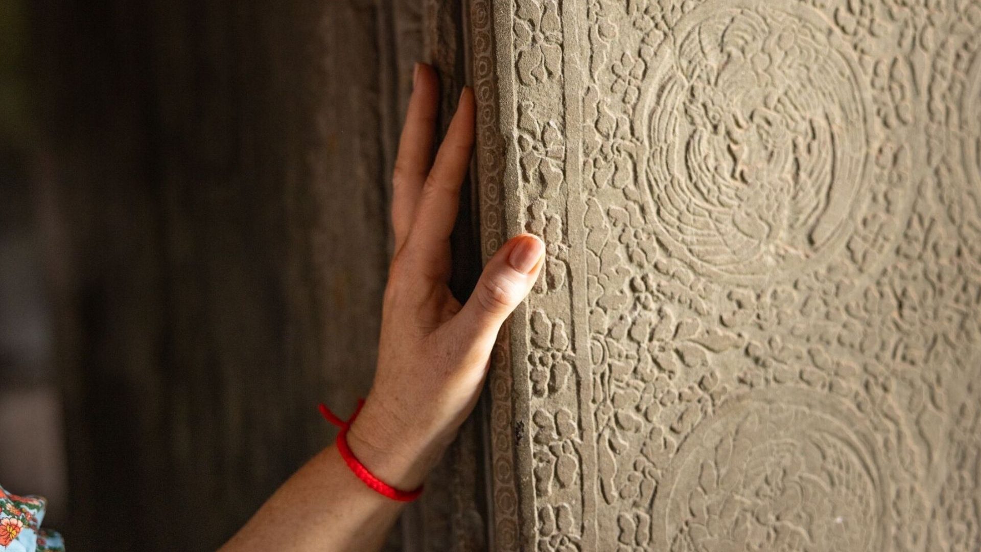 An image of a hand against a pillar carving inside a temple.