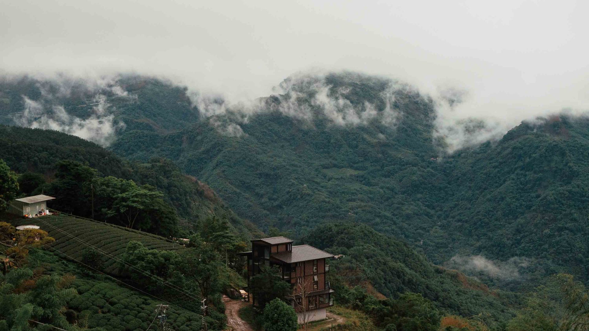 Mountains tower over a small wooden hut.