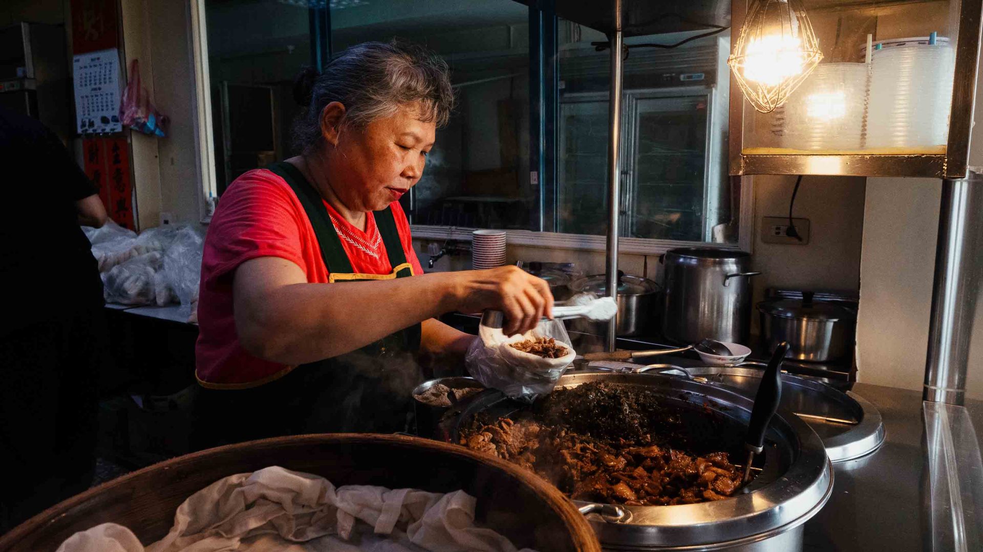 A woman cooks over several pans.