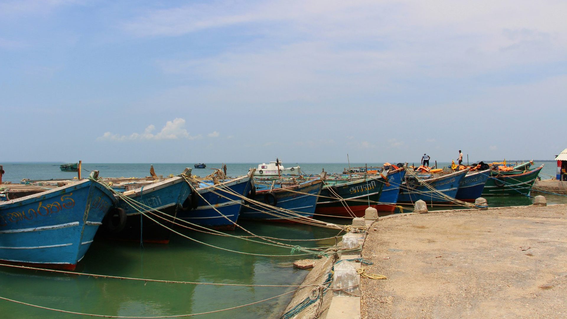 Blue boats are tied up to a concrete dock